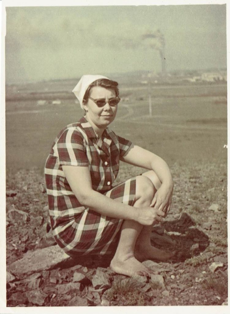 Tamara is sitting on a hill with the power plant of Topar in the background