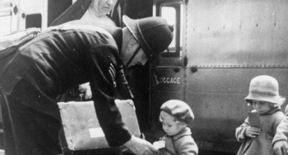 a soldier, a nun and two little girls in front of a train