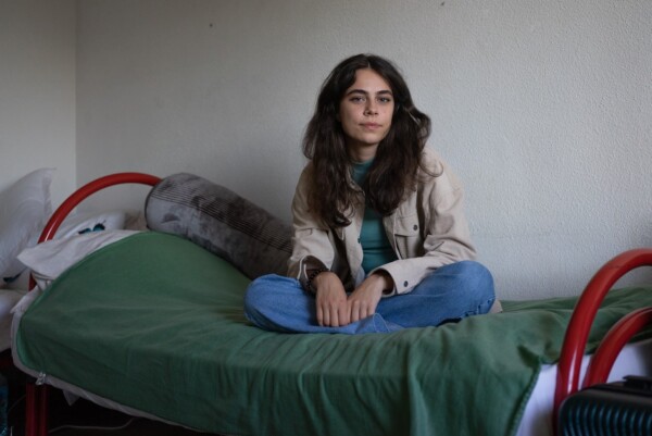 A young Romanian student sitting on her bed.