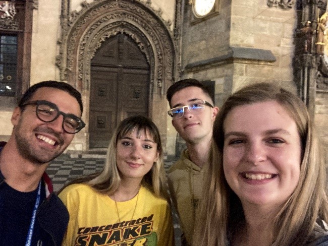 Four young people smiling in front of a church