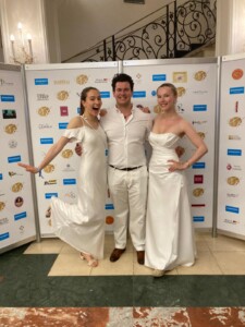 2 women and one man dressed in elegant white clothes at the ball