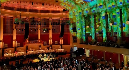 A hall full of people dancing beneath a green, shimmering ceiling