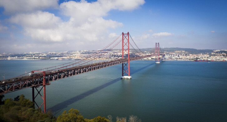 The 25 de Abril Bridge in Lisbon, a red metallic hanging bridge that crosses over the Tagus River